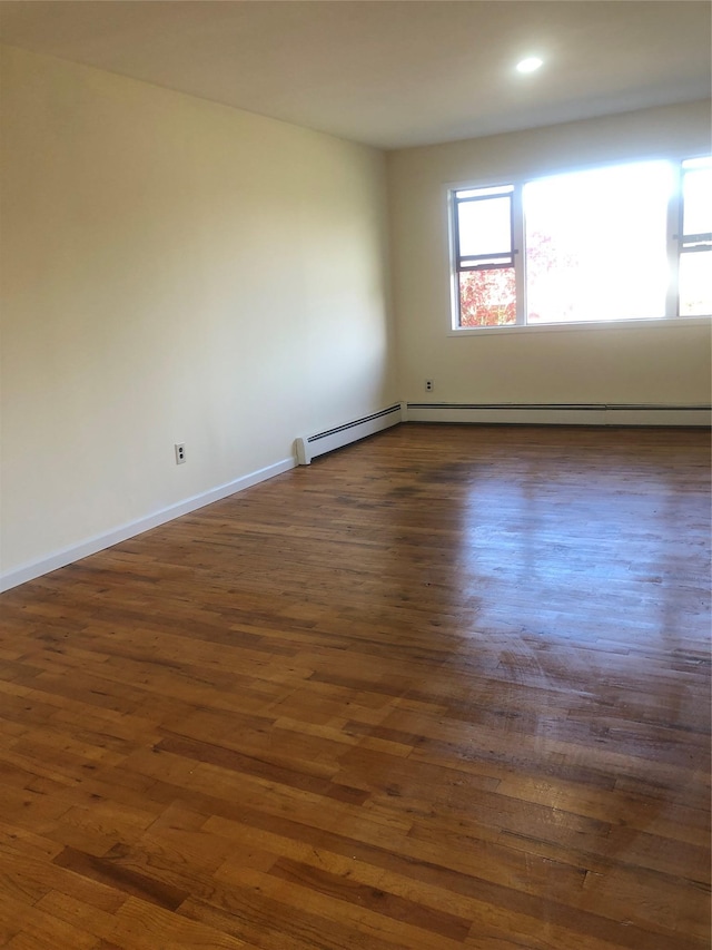 spare room featuring dark wood-type flooring, recessed lighting, baseboards, and a baseboard heating unit