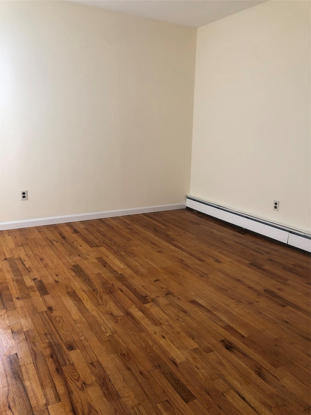 unfurnished room with baseboards, a baseboard heating unit, and hardwood / wood-style floors