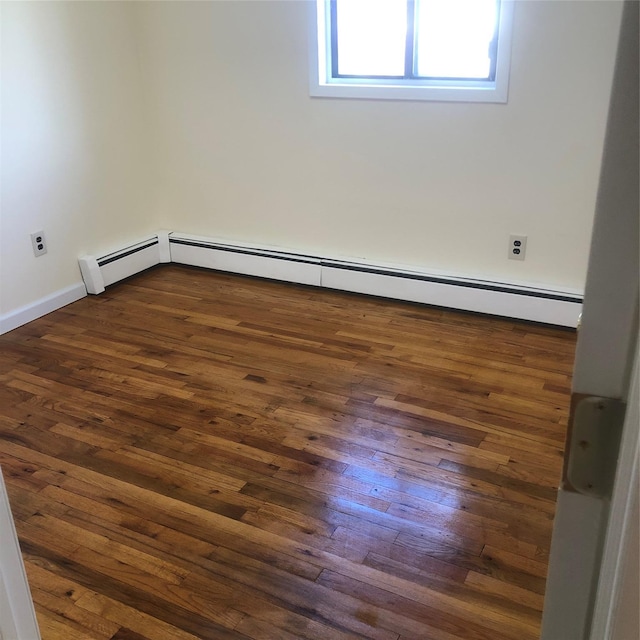 spare room with baseboards, dark wood finished floors, and a baseboard radiator
