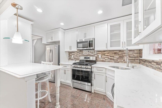 3135 Gunther Ave, Bronx, NY 10469 - kitchen with a sink, a kitchen breakfast bar, stainless steel appliances, white cabinetry, and decorative backsplash