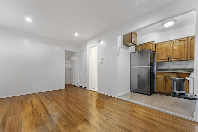 3135 Gunther Ave, Bronx, NY 10469 - kitchen featuring freestanding refrigerator, light wood-style floors, baseboards, brown cabinets, and backsplash