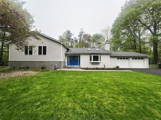 split level home with an attached garage, a chimney, driveway, and a front lawn