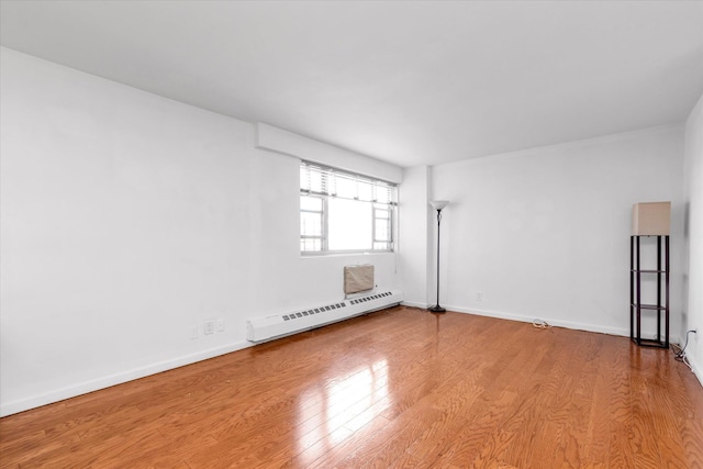 unfurnished room featuring baseboards, a baseboard radiator, and wood finished floors