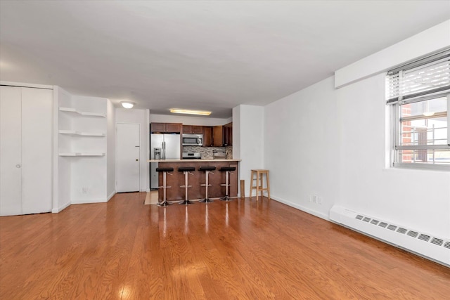 living room with baseboards, baseboard heating, and light wood-style flooring