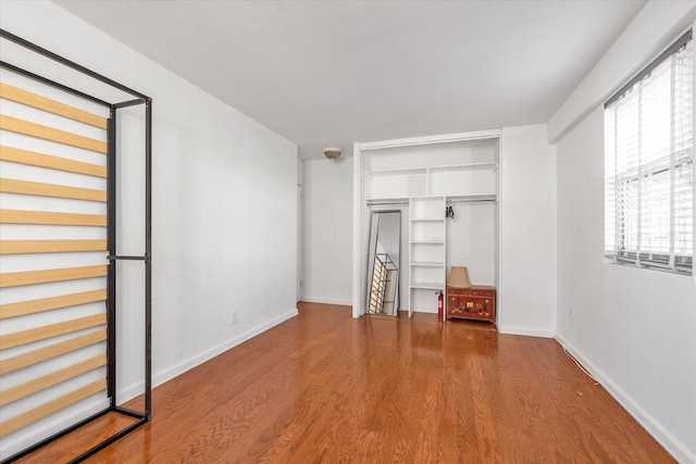 unfurnished bedroom with baseboards, a closet, and wood finished floors