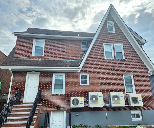 view of front of home featuring a shingled roof, ac unit, and brick siding