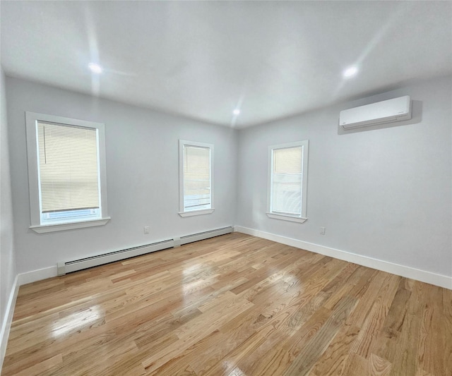 empty room featuring baseboards, a baseboard radiator, a wall mounted AC, and light wood-type flooring
