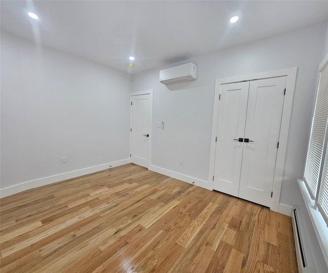 spare room featuring recessed lighting, a baseboard radiator, a wall unit AC, and light wood-type flooring