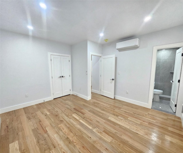 interior space with baseboards, light wood-style flooring, and a wall mounted air conditioner