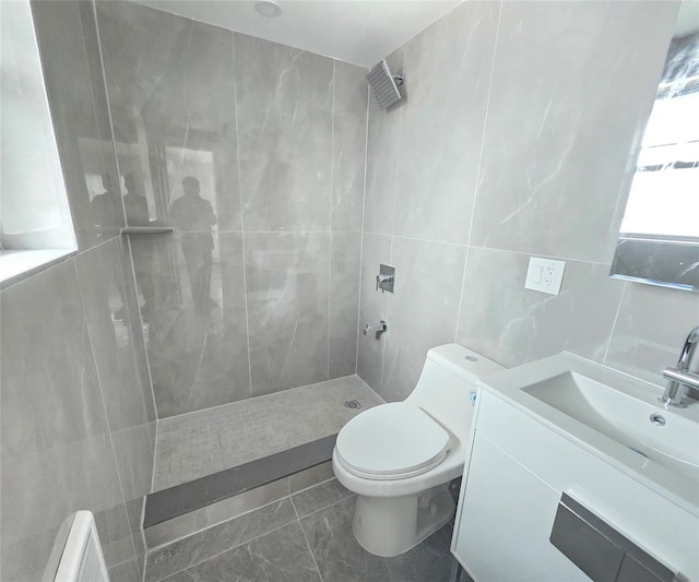 bathroom featuring vanity, tile walls, a tile shower, and toilet
