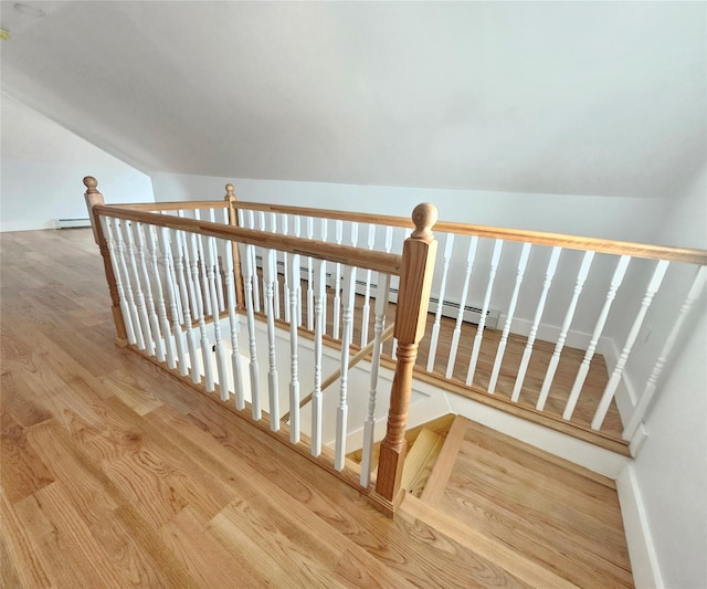 stairway with baseboards, wood finished floors, and vaulted ceiling