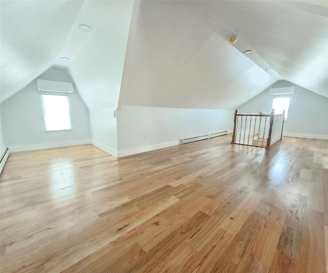 bonus room featuring baseboard heating, vaulted ceiling, a wall mounted air conditioner, baseboards, and light wood-style floors