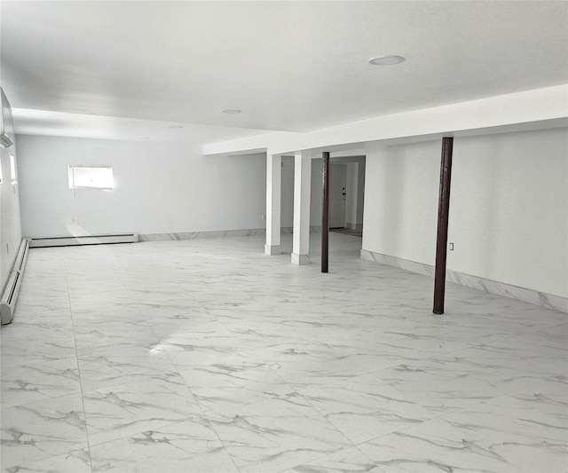 finished below grade area featuring baseboards, baseboard heating, and marble finish floor