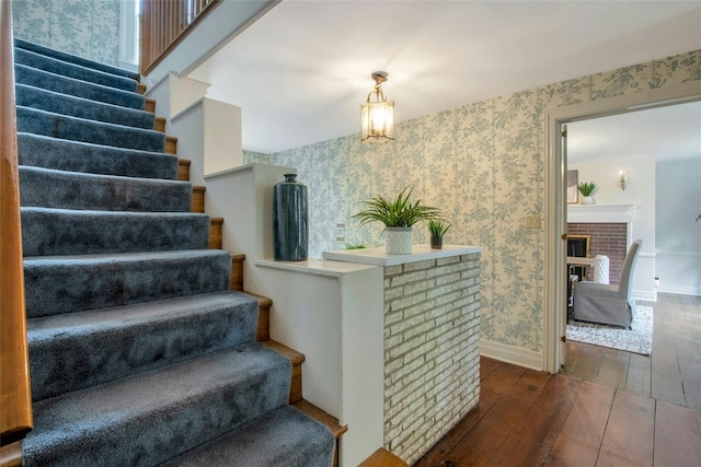 711 Homestead Ave, Maybrook, NY 12543 - stairway featuring a brick fireplace, baseboards, hardwood / wood-style floors, and wallpapered walls