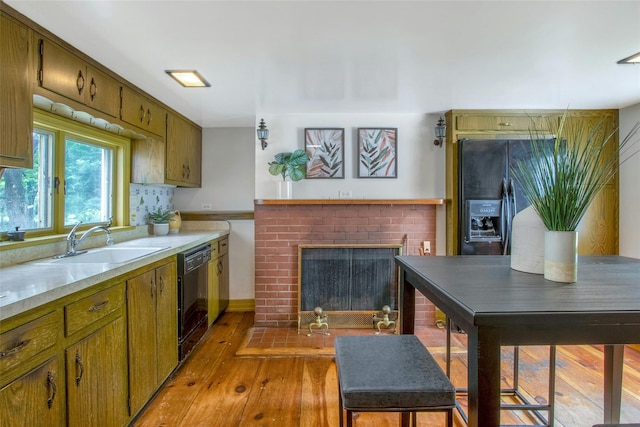 711 Homestead Ave, Maybrook, NY 12543 - kitchen featuring a sink, light wood-type flooring, black appliances, a brick fireplace, and light countertops