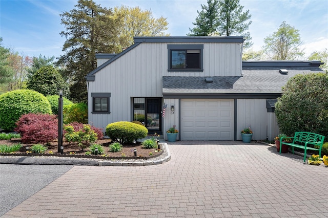view of front facade featuring board and batten siding, decorative driveway, a shingled roof, and a garage