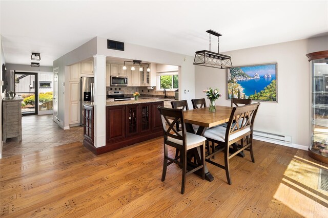 dining space featuring visible vents, light wood finished floors, baseboards, and baseboard heating
