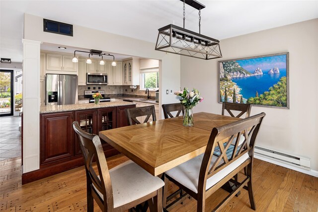 dining area featuring visible vents, a baseboard radiator, and light wood-style floors