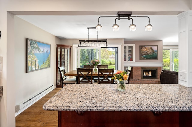 dining area with a fireplace, dark wood-style flooring, and a baseboard radiator