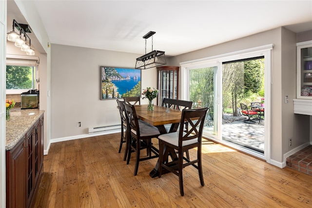 dining space with baseboards, a baseboard heating unit, and light wood-type flooring