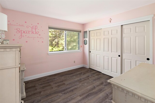 unfurnished bedroom featuring baseboards, dark wood finished floors, and a closet