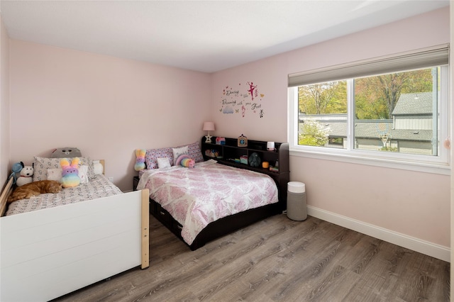 bedroom featuring baseboards, multiple windows, and wood finished floors