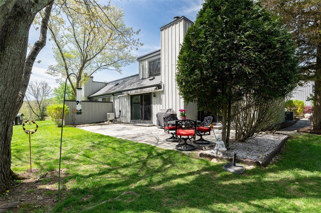 back of house with a lawn, a chimney, and a patio area