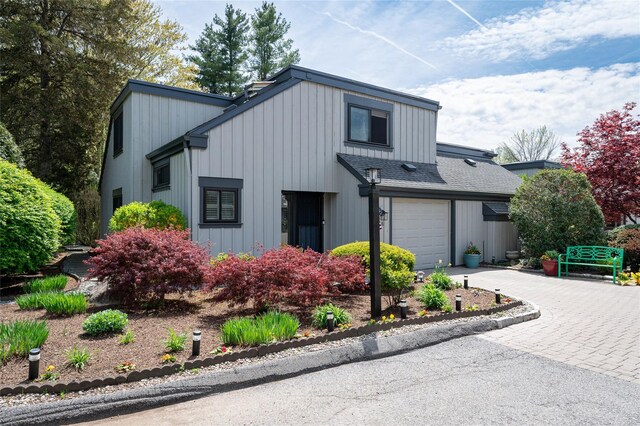 view of front of house featuring roof with shingles, board and batten siding, and driveway