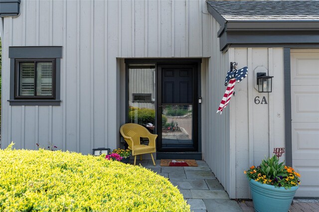 property entrance with roof with shingles and board and batten siding