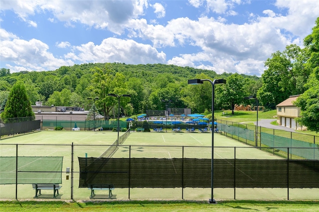 view of tennis court with a view of trees and fence