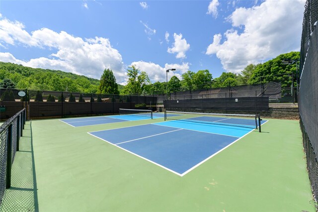 view of tennis court featuring fence and community basketball court