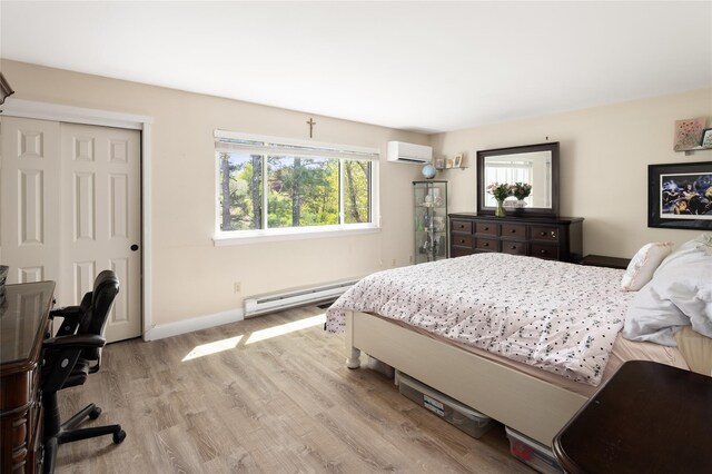 bedroom featuring a closet, light wood-style floors, baseboards, a wall mounted AC, and a baseboard radiator