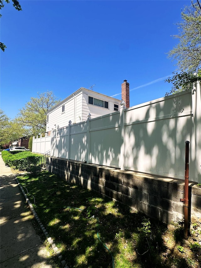 view of side of property featuring fence and a chimney