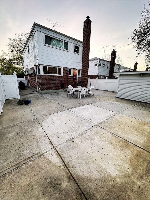 back of property with a fenced backyard, a patio, a chimney, and brick siding
