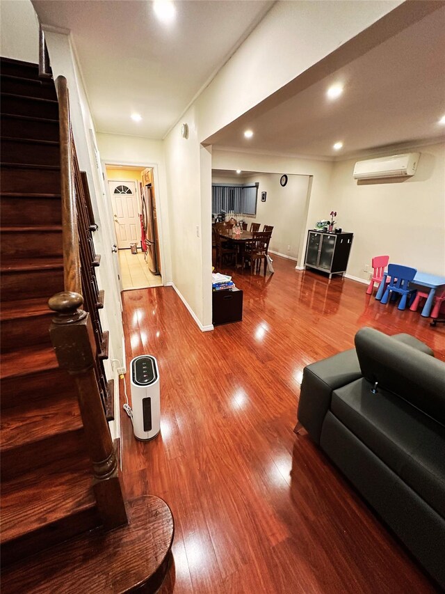 living room with an AC wall unit, recessed lighting, stairs, and wood finished floors