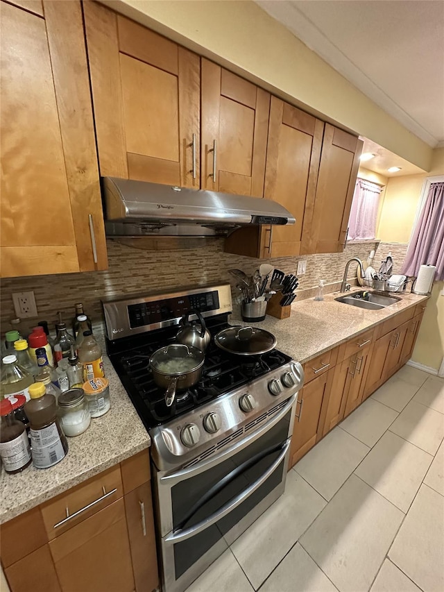 kitchen with under cabinet range hood, double oven range, a sink, and tasteful backsplash