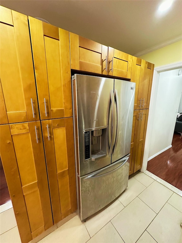 kitchen with light tile patterned floors, stainless steel fridge with ice dispenser, and brown cabinets