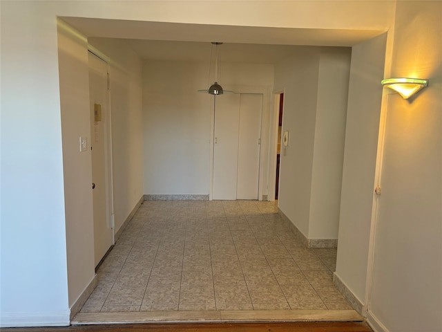 hall featuring light tile patterned floors and baseboards