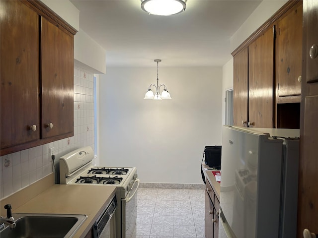kitchen with white appliances, tasteful backsplash, a sink, light tile patterned floors, and a notable chandelier