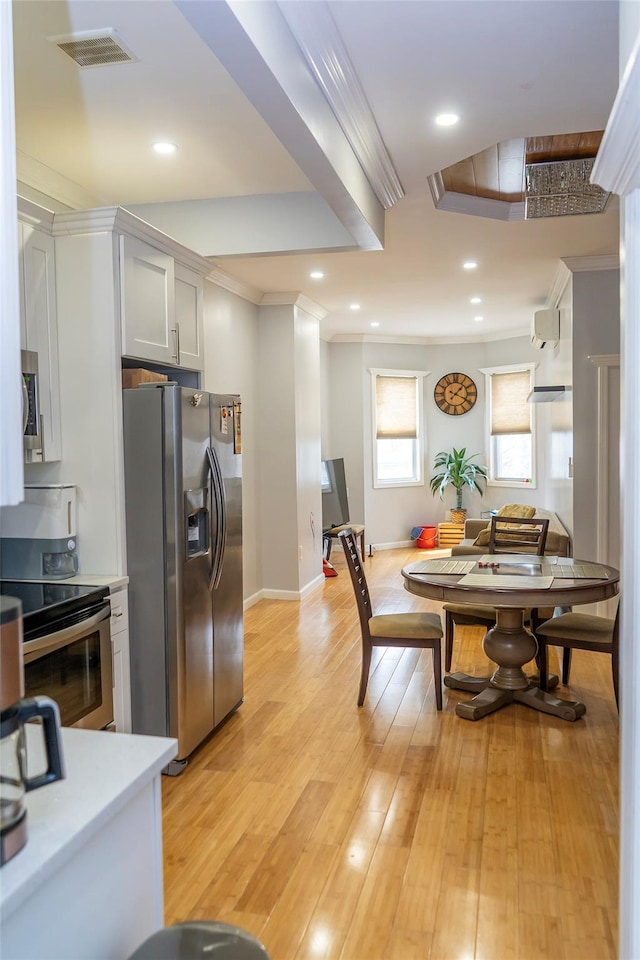 kitchen with visible vents, appliances with stainless steel finishes, light countertops, light wood finished floors, and ornamental molding