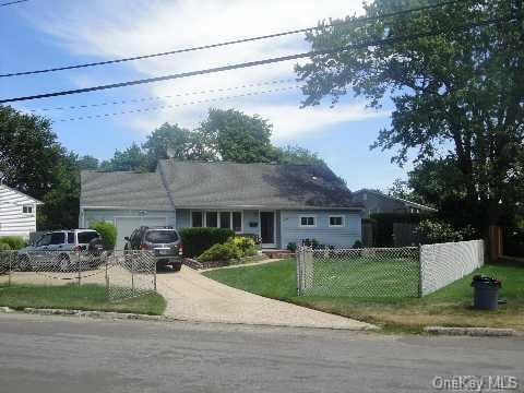 view of front of property with an attached garage, a front lawn, driveway, and fence private yard