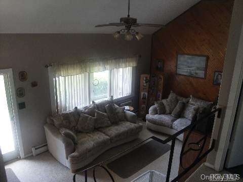 living area with baseboards, ceiling fan, baseboard heating, and vaulted ceiling