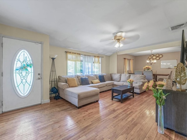 living area with visible vents, light wood-style flooring, and ceiling fan with notable chandelier