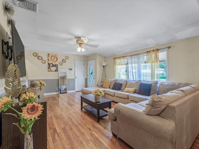 living room featuring light wood-style flooring, baseboards, a ceiling fan, and visible vents