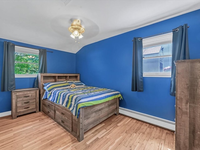 bedroom featuring wood finished floors, a ceiling fan, baseboards, lofted ceiling, and a baseboard radiator