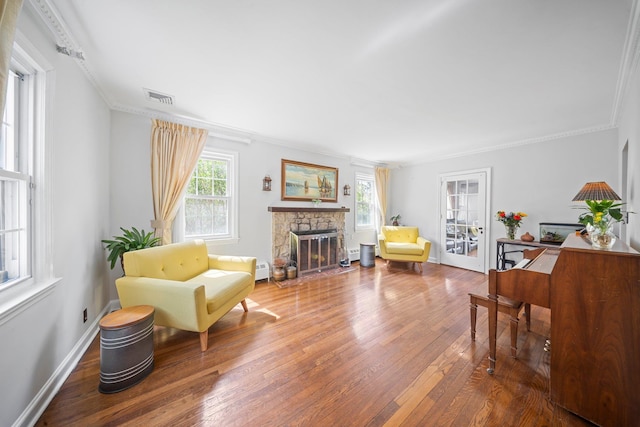 19 Donald St, East Williston, NY 11596 - living area featuring hardwood / wood-style flooring, a stone fireplace, ornamental molding, and baseboards