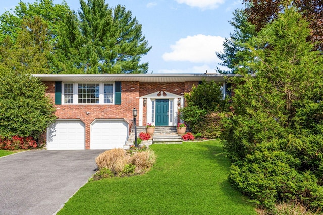 bi-level home with aphalt driveway, a garage, a front lawn, and brick siding