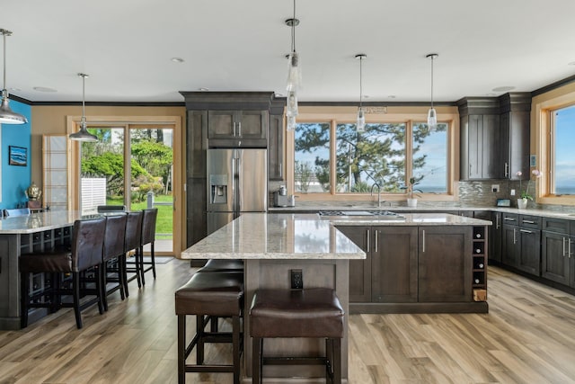 516 Asharoken Ave, Northport, NY 11768 - kitchen featuring a center island, stainless steel appliances, light wood-type flooring, decorative backsplash, and healthy amount of natural light