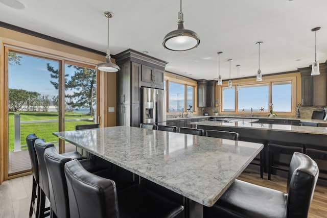 516 Asharoken Ave, Northport, NY 11768 - kitchen featuring stainless steel refrigerator with ice dispenser, a large island, light wood-style flooring, light stone counters, and a breakfast bar area
