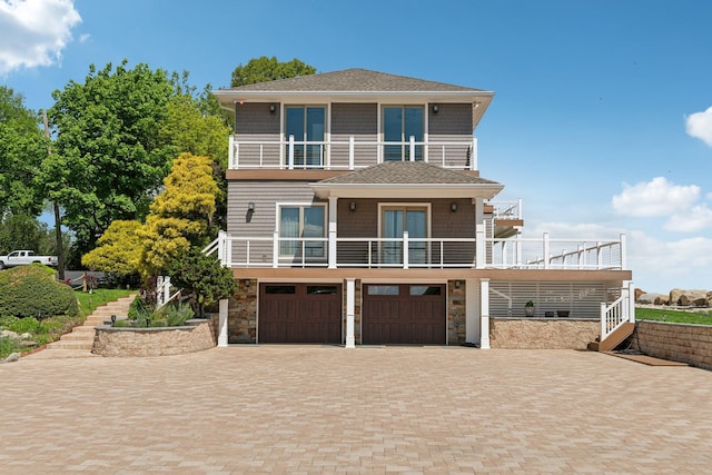 516 Asharoken Ave, Northport, NY 11768 - raised beach house with a balcony, stone siding, a garage, decorative driveway, and a shingled roof